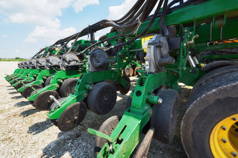 Close up of seeder attached to tractor in field. Agricultural machinery for spring works sowing