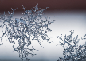 Closeup shot of a snowflake on a glass from frost, with detailed pattern