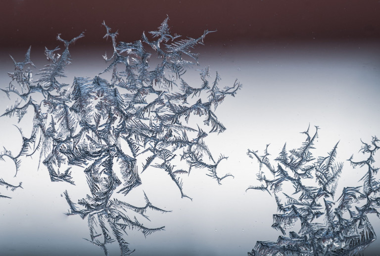 Closeup shot of a snowflake on a glass from frost, with detailed pattern