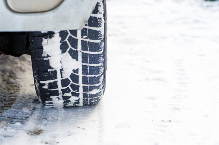 Car tires on winter road covered with snow. Vehicle on snowy all