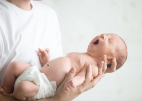 Male hands holding a screaming newborn