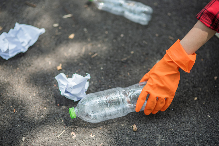 woman collecting garbage in a black bag.